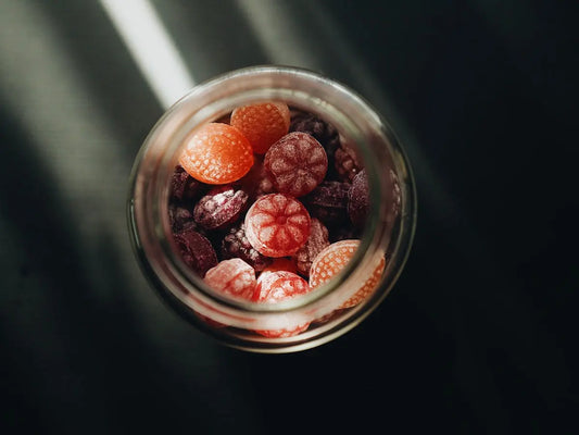 A glass jar filled with raspberries and oranges